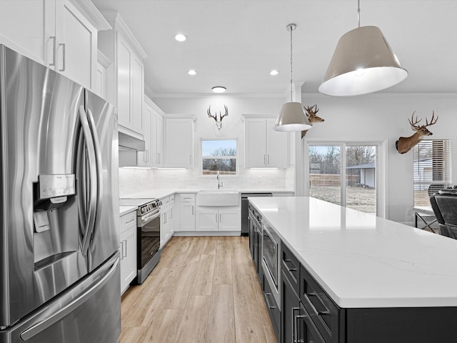 kitchen with appliances with stainless steel finishes, white cabinets, backsplash, hanging light fixtures, and a center island