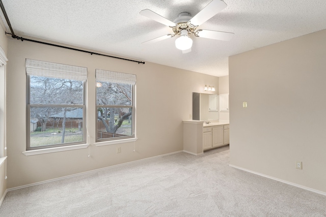 carpeted spare room with sink, a textured ceiling, and ceiling fan