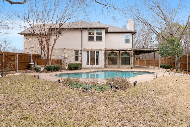 rear view of house with a fenced in pool and a patio