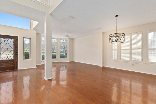 foyer with hardwood / wood-style floors and ceiling fan with notable chandelier