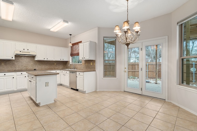 kitchen with pendant lighting, white cabinets, backsplash, a center island, and stainless steel dishwasher