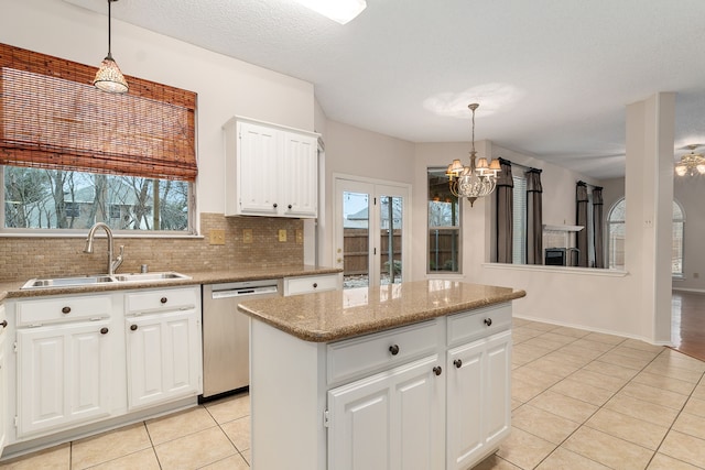 kitchen featuring white cabinetry, stainless steel dishwasher, decorative light fixtures, and sink