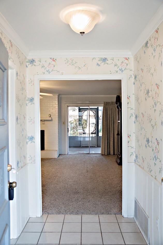 hall with crown molding and light carpet