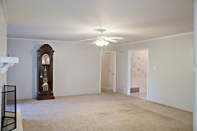 carpeted spare room featuring crown molding, ceiling fan, and a fireplace