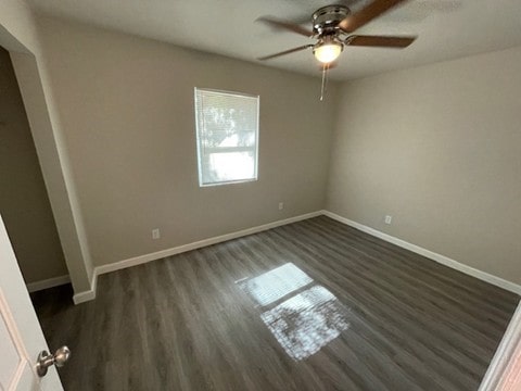 empty room featuring dark wood-type flooring and ceiling fan