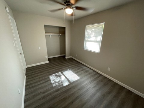 unfurnished bedroom featuring dark hardwood / wood-style floors, ceiling fan, and a closet