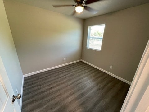 empty room featuring ceiling fan and dark hardwood / wood-style flooring