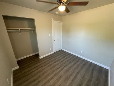 unfurnished bedroom with dark hardwood / wood-style flooring, ceiling fan, and a closet