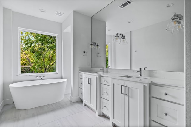 bathroom featuring tile patterned flooring, a bathing tub, a wealth of natural light, and vanity