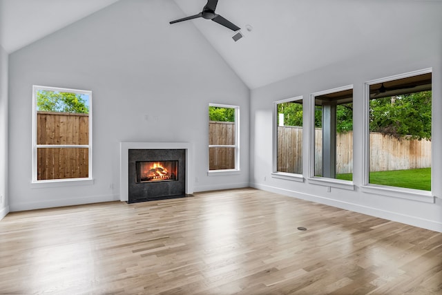 unfurnished living room with a wealth of natural light, high vaulted ceiling, and light hardwood / wood-style floors