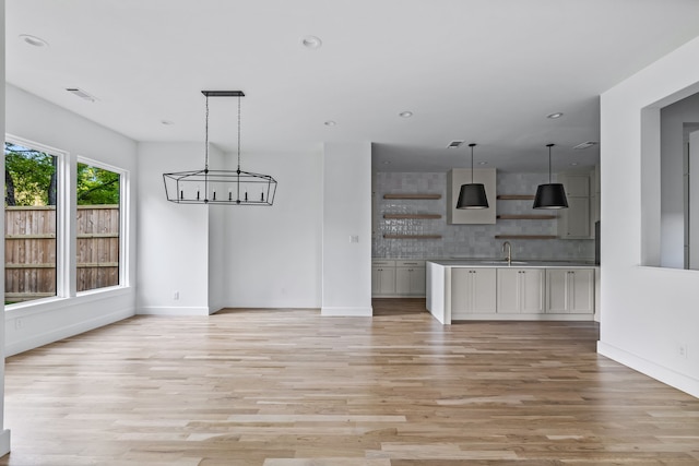 unfurnished dining area featuring sink, a chandelier, and light wood-type flooring