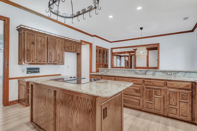 kitchen with black electric stovetop, light wood-style flooring, a kitchen island, ornamental molding, and brown cabinets