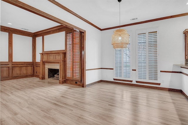 unfurnished living room with baseboards, visible vents, a tile fireplace, wood finished floors, and crown molding