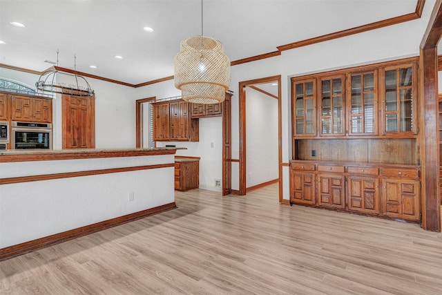 kitchen with brown cabinetry, light wood-style floors, ornamental molding, oven, and baseboards