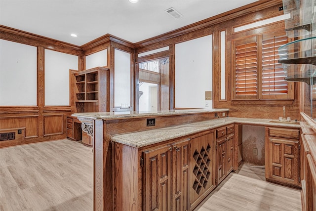 kitchen with brown cabinets, visible vents, light wood-style flooring, and light stone counters