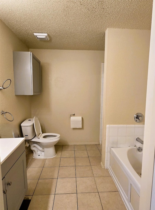 bathroom featuring vanity, toilet, a bath, tile patterned floors, and a textured ceiling