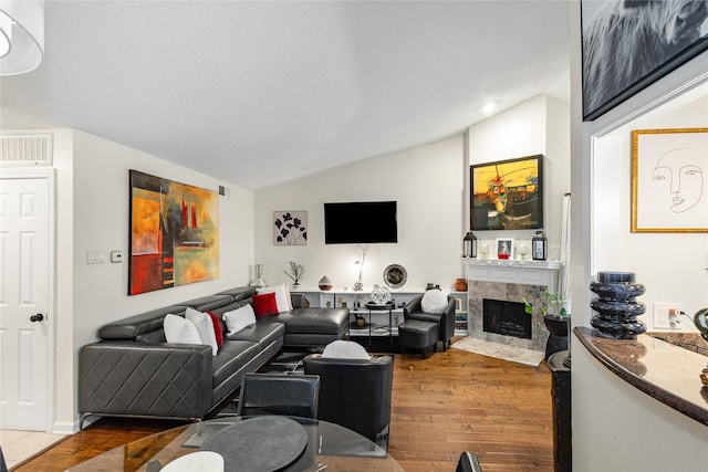 living room featuring hardwood / wood-style flooring, a fireplace, and vaulted ceiling