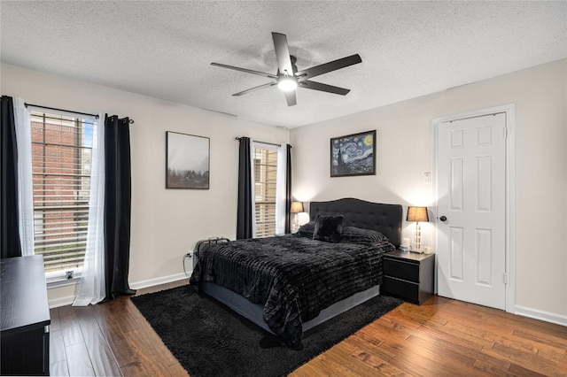 bedroom with dark wood-type flooring, ceiling fan, and a textured ceiling