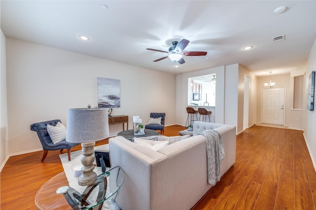 living room with hardwood / wood-style floors and ceiling fan with notable chandelier