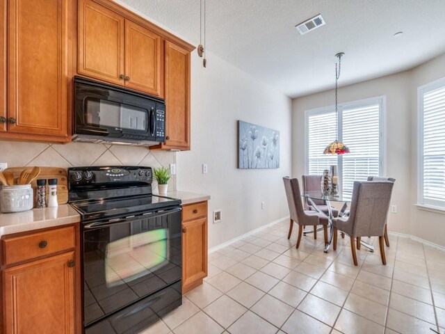 kitchen with tasteful backsplash, a textured ceiling, light tile patterned floors, pendant lighting, and black appliances