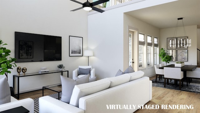 living room with ceiling fan with notable chandelier and light hardwood / wood-style flooring