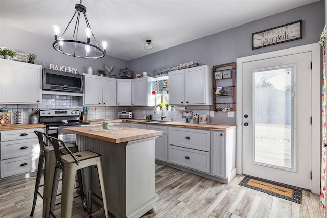 kitchen featuring pendant lighting, butcher block counters, a breakfast bar area, a center island, and stainless steel appliances