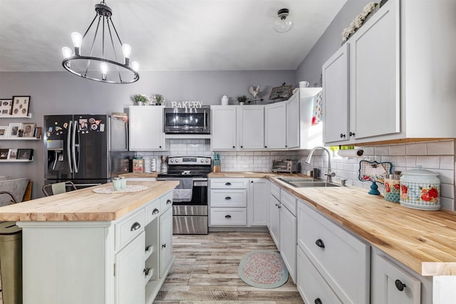kitchen featuring appliances with stainless steel finishes, butcher block countertops, and white cabinets