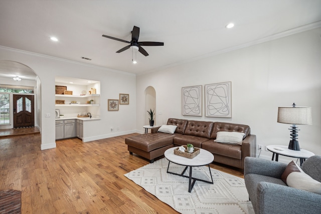 living room featuring crown molding, ceiling fan, and light hardwood / wood-style flooring