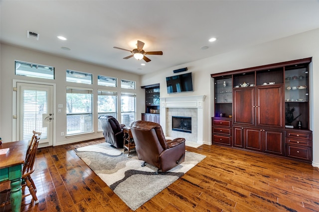 living room featuring ceiling fan, a fireplace, and dark hardwood / wood-style flooring