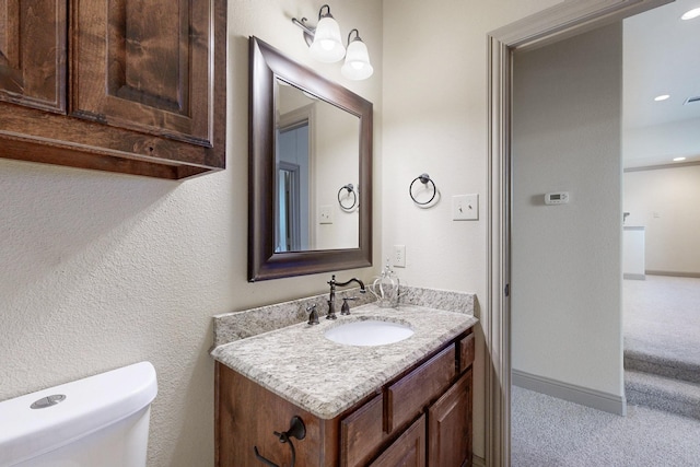 half bathroom featuring baseboards, vanity, and toilet