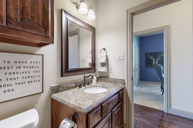 bathroom featuring baseboards, vanity, and toilet