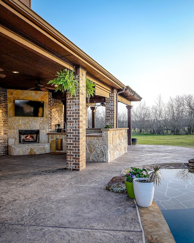 view of patio with a ceiling fan and an outdoor stone fireplace