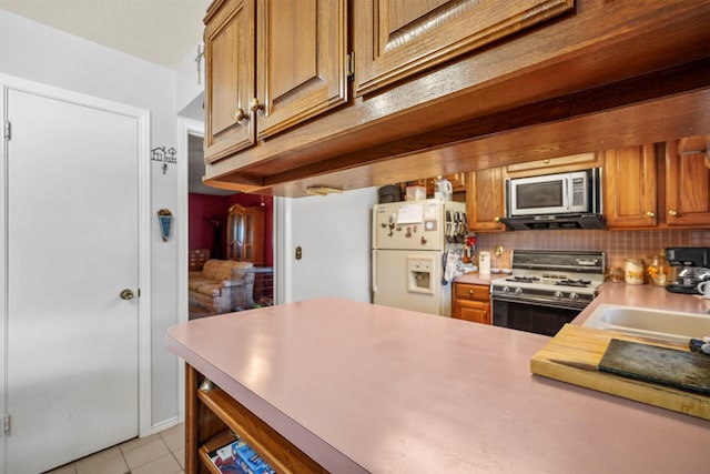 kitchen with tasteful backsplash, light tile patterned flooring, sink, and white appliances