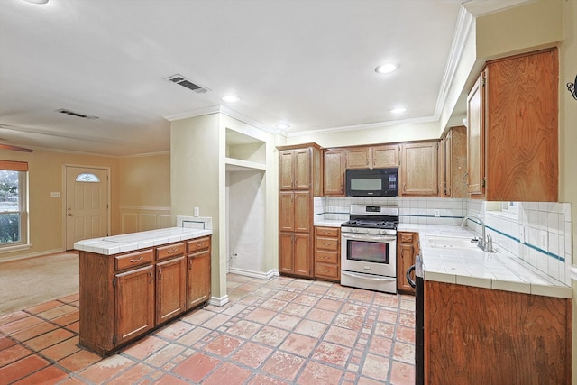 kitchen with sink, stainless steel gas range, decorative backsplash, tile countertops, and kitchen peninsula