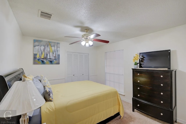 bedroom featuring ceiling fan, carpet, a closet, and a textured ceiling