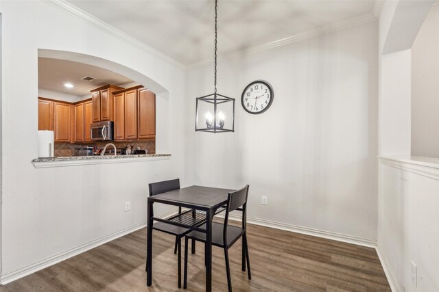 dining area featuring dark wood-type flooring and crown molding