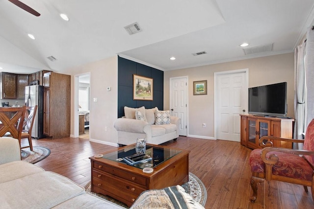 living room with ornamental molding, dark wood-type flooring, and ceiling fan