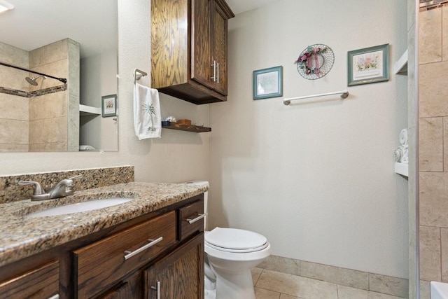 bathroom featuring tile patterned flooring, vanity, toilet, and a tile shower