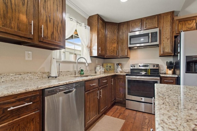 kitchen featuring sink, light stone counters, ornamental molding, dark hardwood / wood-style floors, and stainless steel appliances