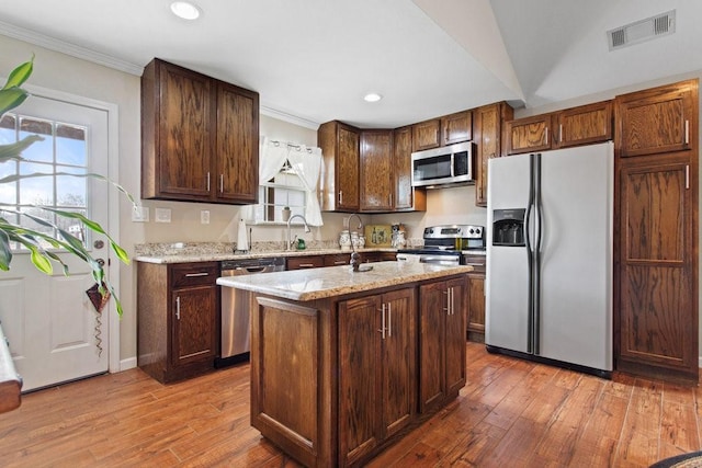 kitchen with light stone counters, appliances with stainless steel finishes, a kitchen island, and plenty of natural light