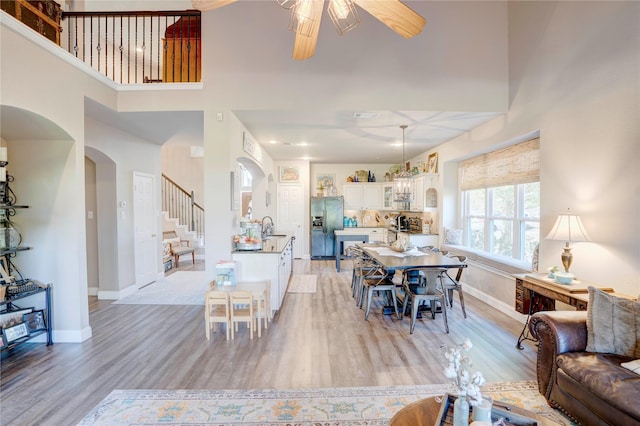 dining space with sink, light hardwood / wood-style flooring, and a high ceiling