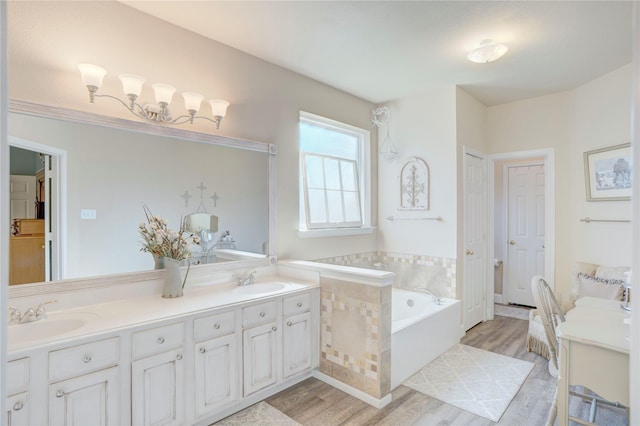 bathroom featuring hardwood / wood-style flooring, vanity, and a relaxing tiled tub