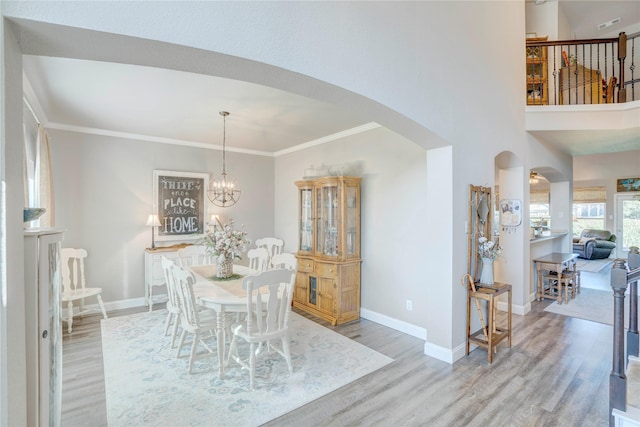 dining area with crown molding, a notable chandelier, and light wood-type flooring