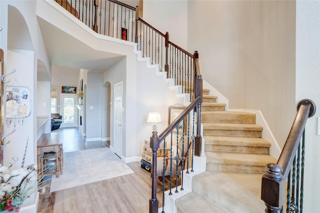 stairway featuring wood-type flooring and a towering ceiling