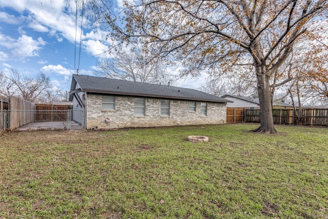 rear view of property featuring a lawn and an outdoor fire pit