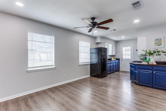 kitchen with black refrigerator, ceiling fan, blue cabinets, and light hardwood / wood-style floors