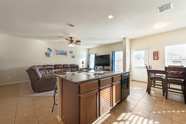 kitchen featuring light tile patterned floors, sink, an island with sink, and dishwasher