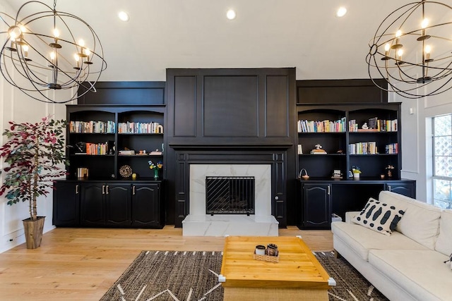 living room with a fireplace, a chandelier, and light wood-type flooring