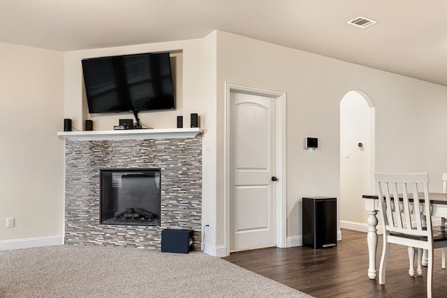 living room with a fireplace and dark colored carpet