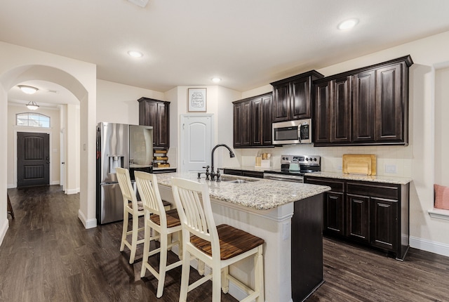 kitchen featuring sink, appliances with stainless steel finishes, a kitchen island with sink, a kitchen breakfast bar, and dark hardwood / wood-style floors